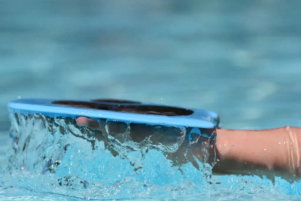 A swimmer using a training paddle in the pool